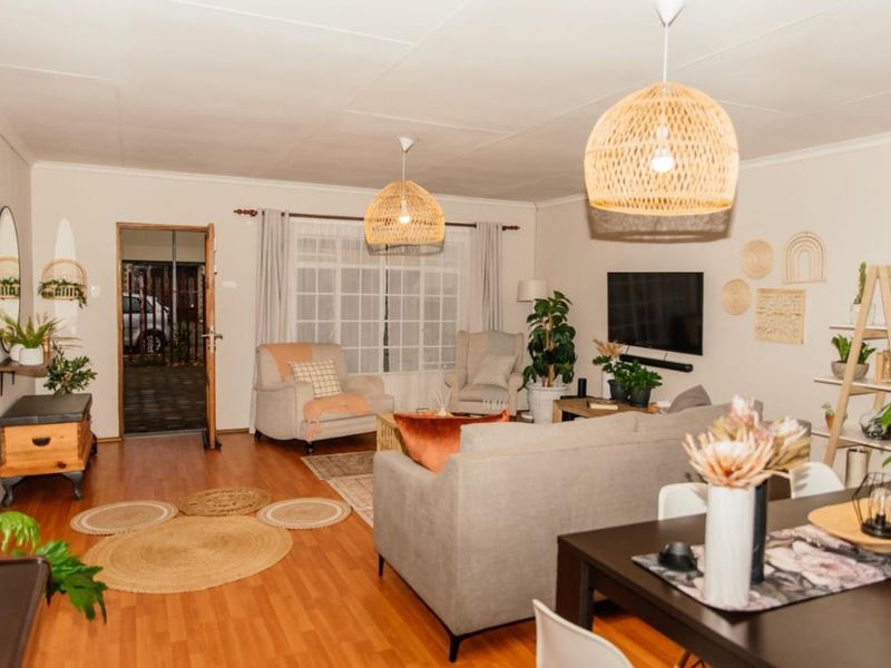 Spacious open-plan living and dining area featuring laminate flooring, neutral walls, and direct access to the exterior through a sliding door.