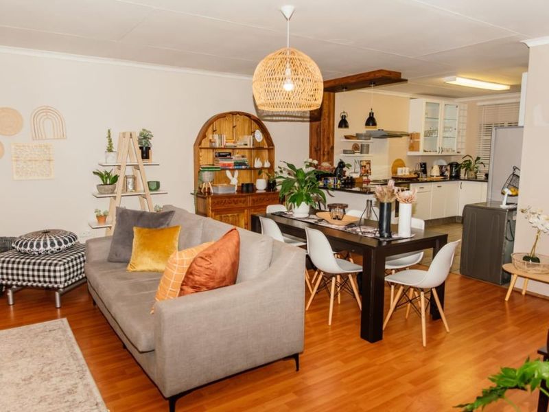 Open-plan living and dining area featuring laminate flooring and a functional kitchen with built-in cabinetry and an extractor fan.