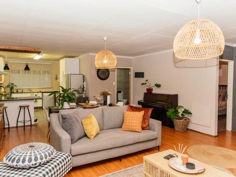 Open-plan living and dining area featuring laminate flooring, integrated kitchen space, and neutral wall tones, creating a functional and connected living environment.