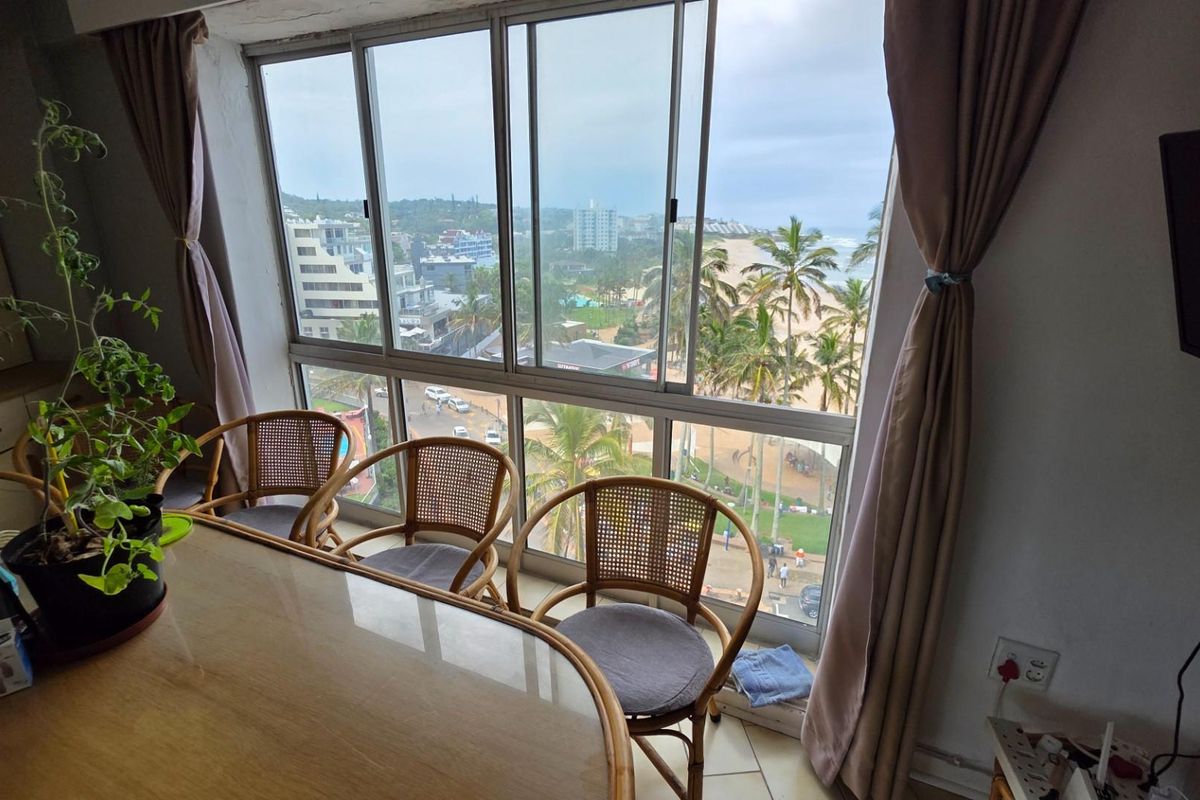 A living area featuring large floor-to-ceiling windows with expansive coastal and urban views, providing ample natural light.
