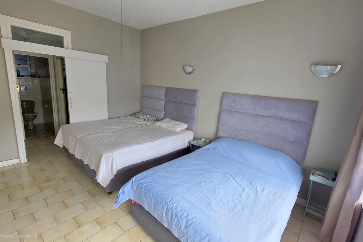 A bedroom featuring tiled flooring, wall-mounted lighting fixtures, and an en-suite bathroom access point.