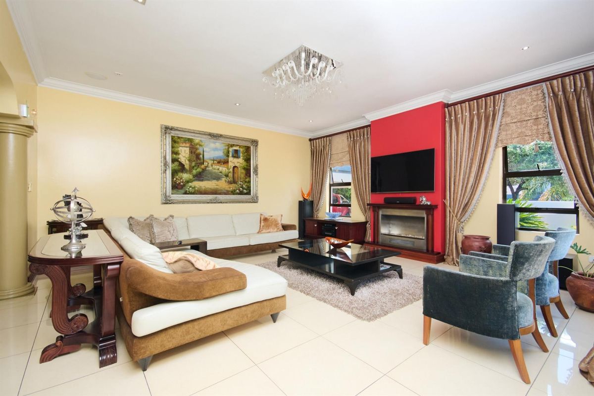 Spacious living room featuring tiled flooring, a central fireplace with a red accent wall, and decorative crown molding.