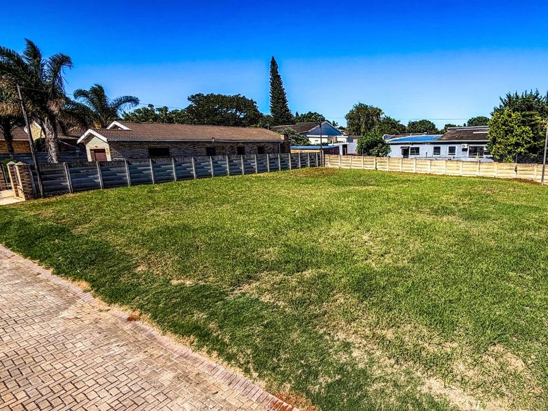 A level, grassed residential vacant stand featuring perimeter precast concrete walling and paved street frontage in an established neighborhood.