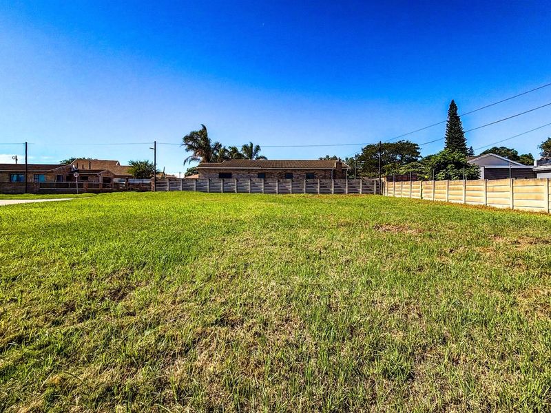 A vacant residential plot featuring level grass terrain, enclosed by precast concrete perimeter walling in a established neighborhood setting.