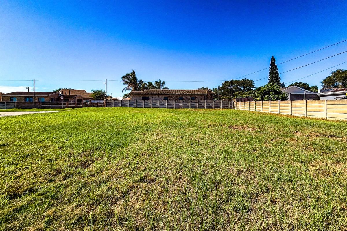 A vacant residential plot featuring level grass terrain, enclosed by precast concrete perimeter walling in a established neighborhood setting.