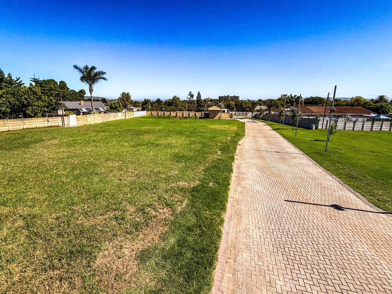 A spacious, level residential vacant land plot featuring a paved driveway, established lawn, and perimeter walling, ready for development.