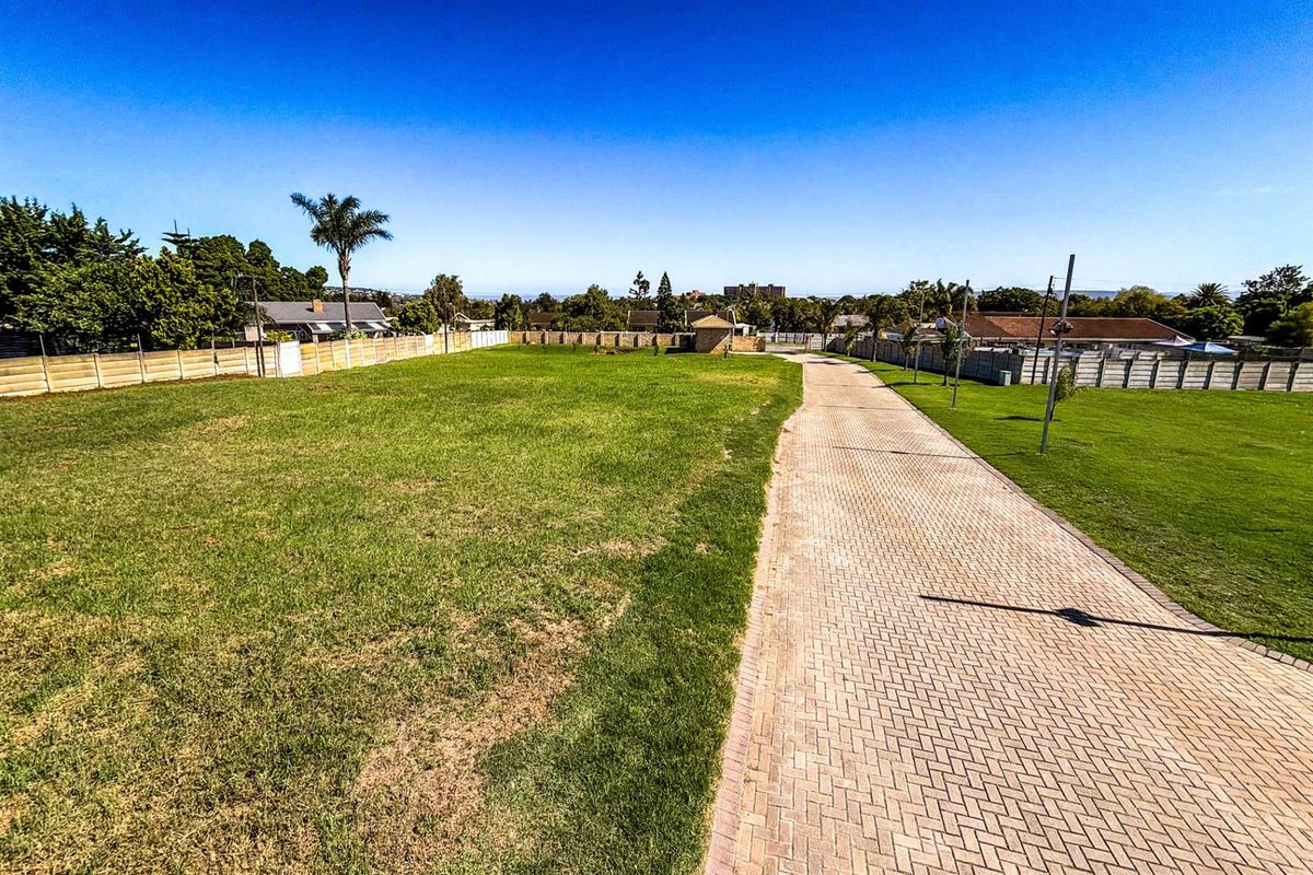 A spacious, level residential vacant land plot featuring a paved driveway, established lawn, and perimeter walling, ready for development.