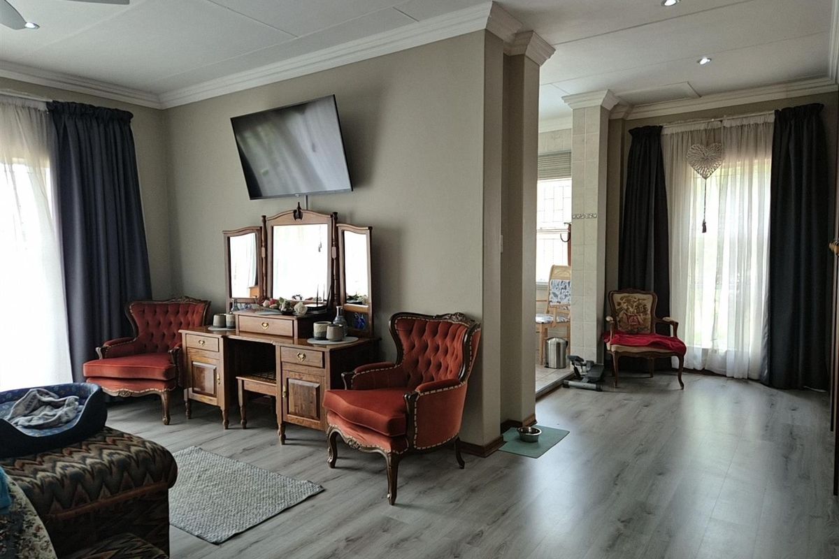 Spacious living area featuring modern laminate flooring, crown molding, and recessed lighting, with an open-plan layout connecting to an adjacent room.