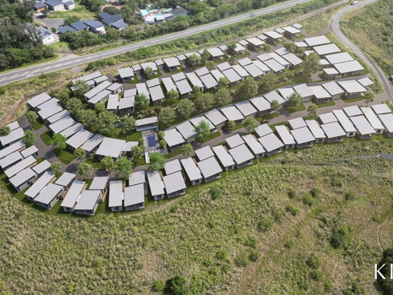 Aerial view of a modern residential estate development featuring multiple housing units, communal pool area, and landscaped surroundings.