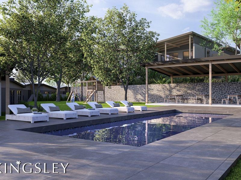 A modern outdoor pool area featuring a tiled deck, stone retaining wall, and a covered patio space, perfect for outdoor relaxation and entertainment.