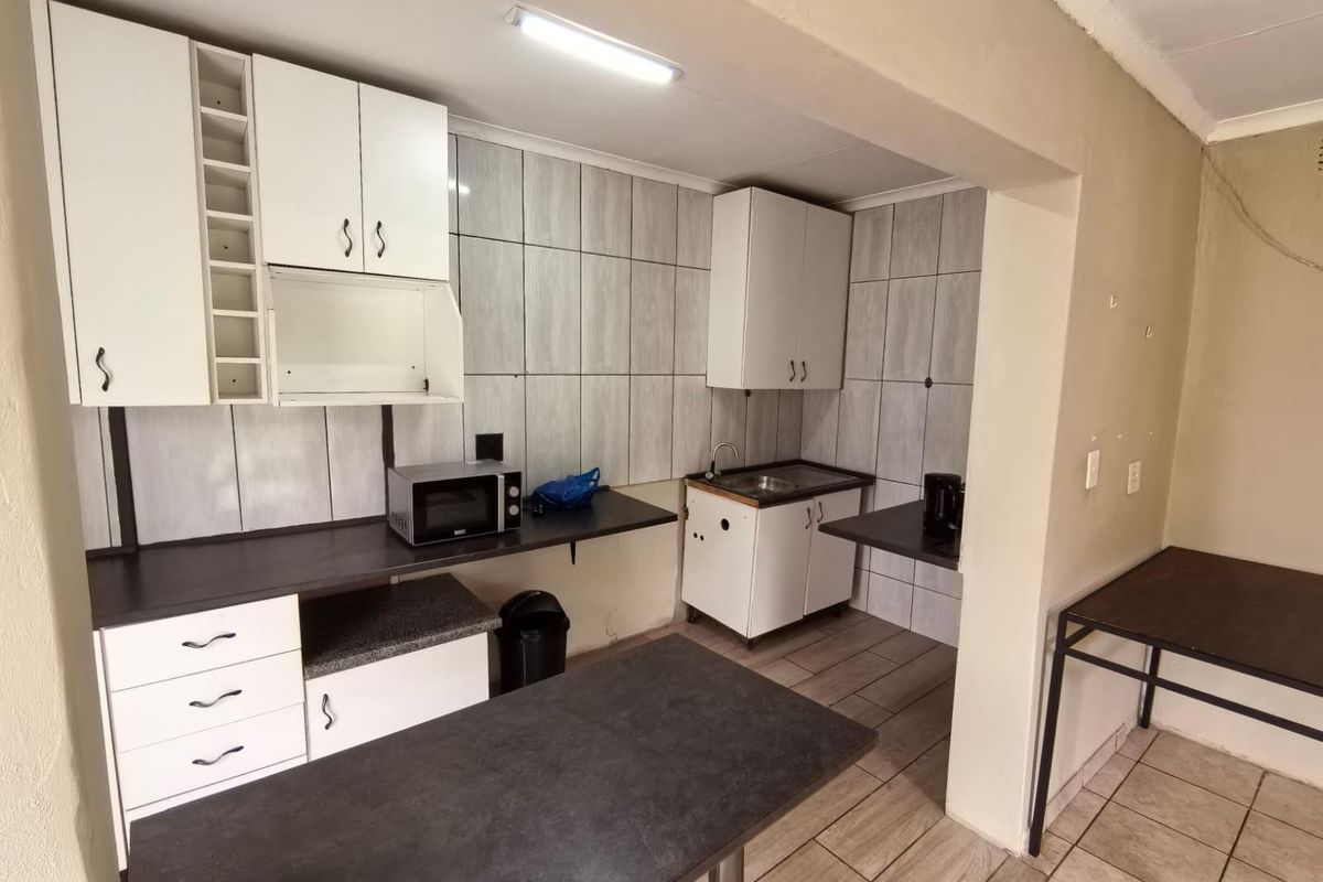 Functional kitchen area featuring white cabinetry, dark countertops, tiled splashbacks, and a compact sink setup, offering a practical layout for daily use.