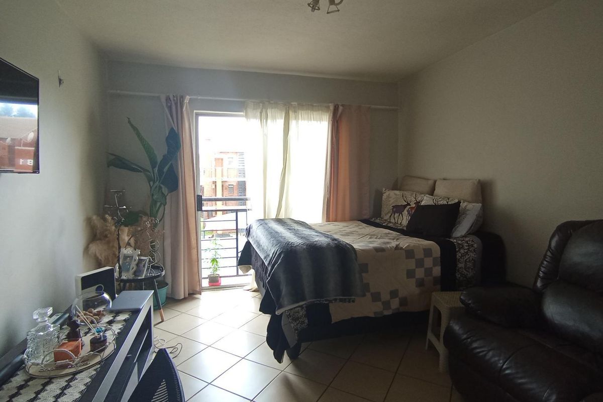 A bedroom featuring tiled flooring and a sliding glass door that opens onto a private balcony, providing natural light.
