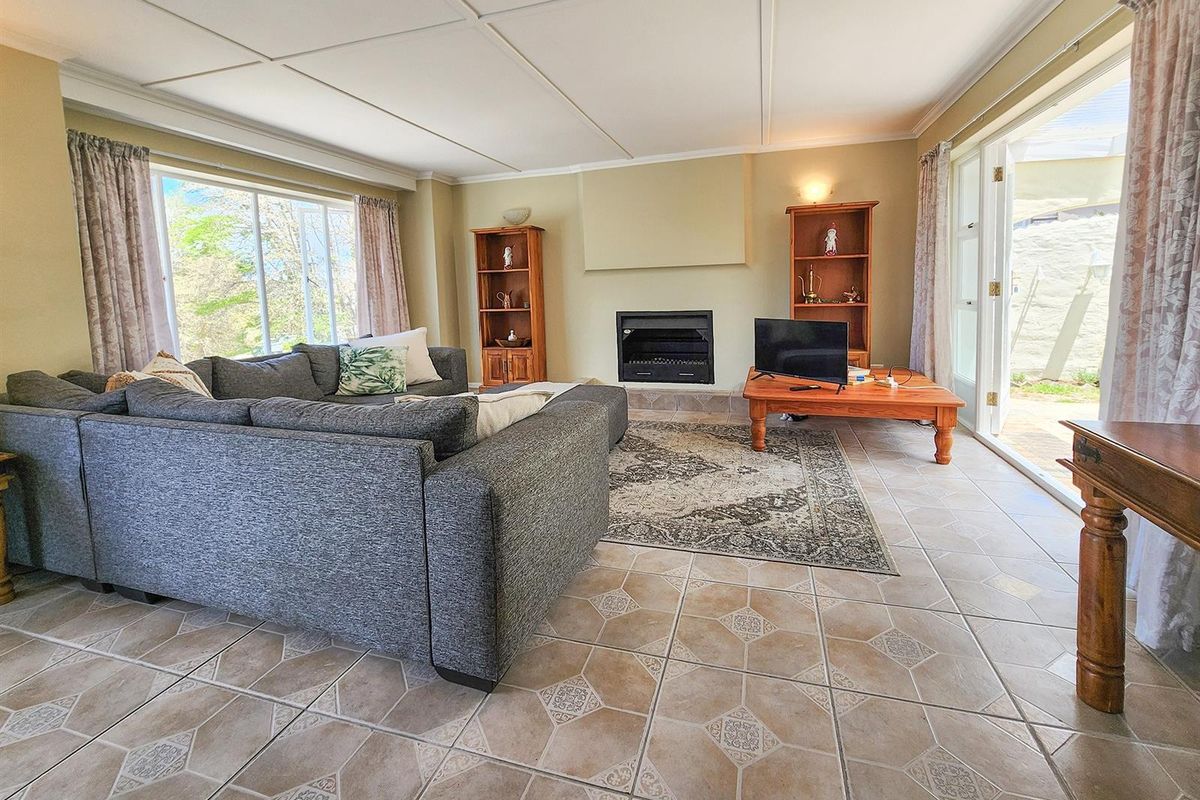 Spacious living room featuring a built-in fireplace, tiled flooring, and large windows providing natural light with direct access to the outdoor patio area.