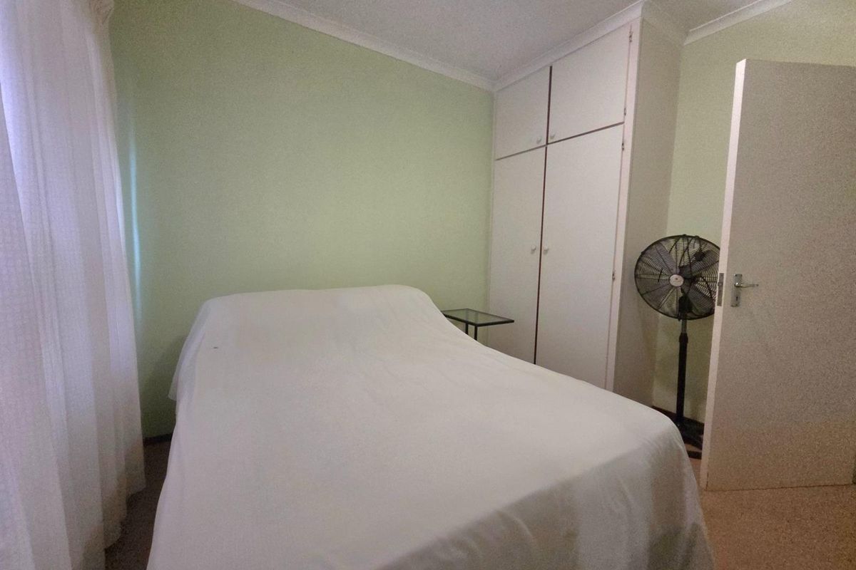 A functional bedroom featuring built-in cupboards, neutral wall finishes, and carpeted flooring, providing a practical and comfortable living space.