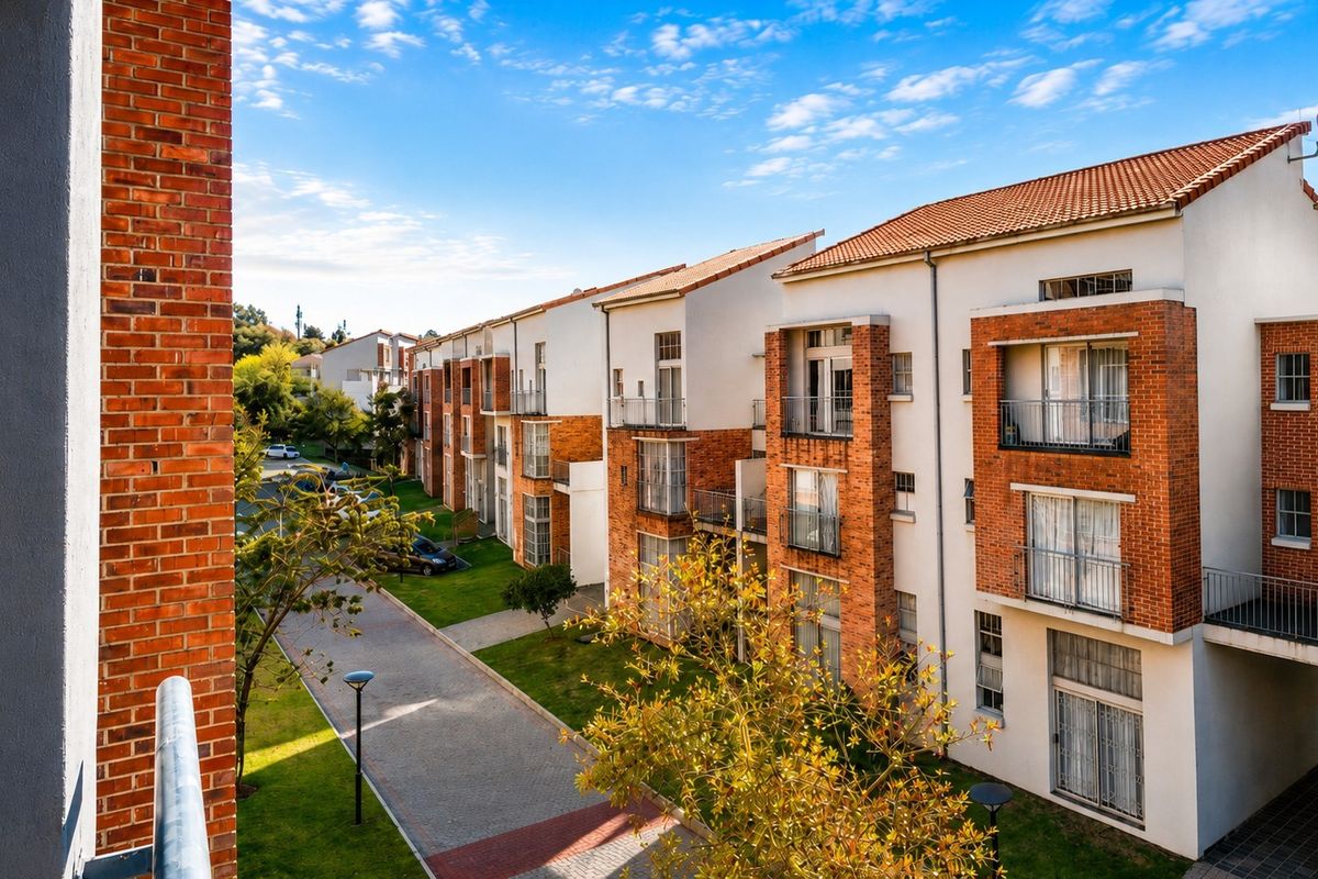 Exterior view of a multi-story apartment complex featuring brick and plaster facades, private balconies, and well-maintained communal gardens and paved driveways.