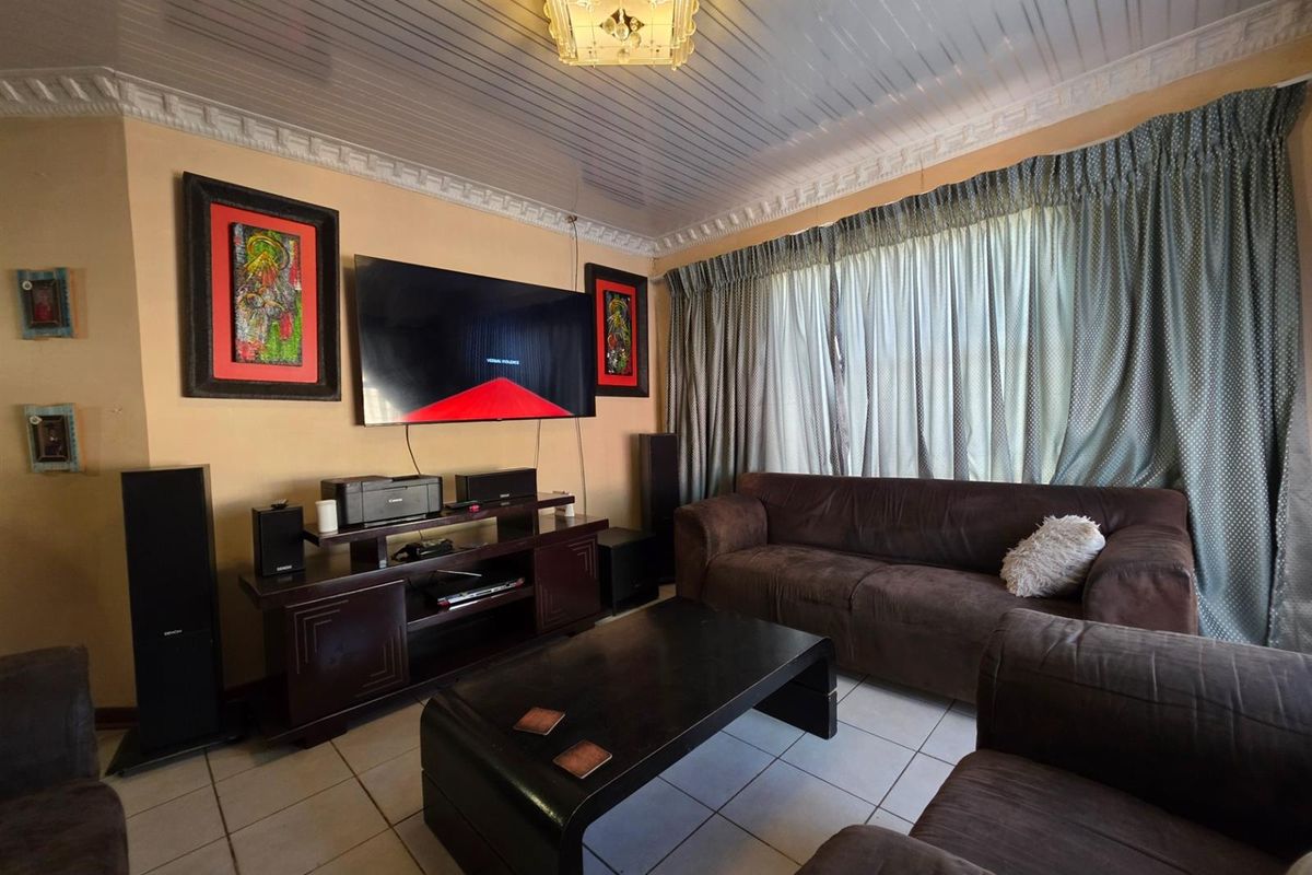 A living room featuring tiled flooring, a decorative ceiling with crown molding, and large window treatments.