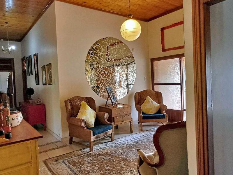 A living area featuring a timber ceiling and tiled flooring, providing a warm and traditional atmosphere with access to adjacent rooms.