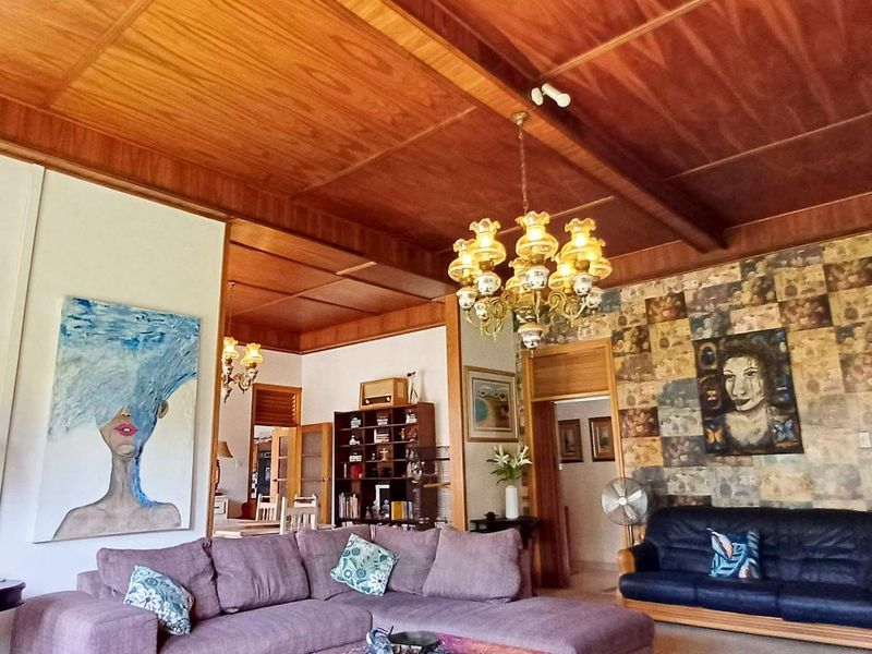 Spacious living room featuring a distinctive timber panelled ceiling with exposed beams and an ornate chandelier, offering a warm and traditional aesthetic.