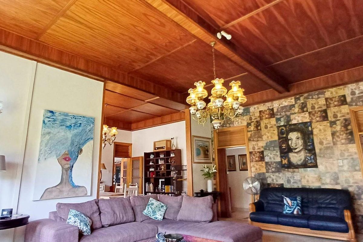 Spacious living room featuring a distinctive timber panelled ceiling with exposed beams and an ornate chandelier, offering a warm and traditional aesthetic.