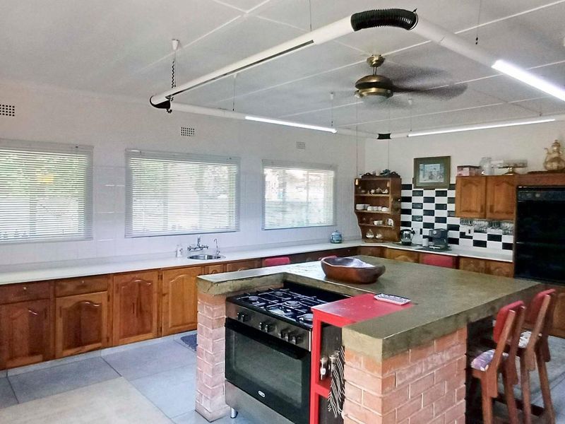 Spacious kitchen featuring extensive wooden cabinetry, a central brick-based island with a gas cooktop, and ample counter space with a tiled splashback.