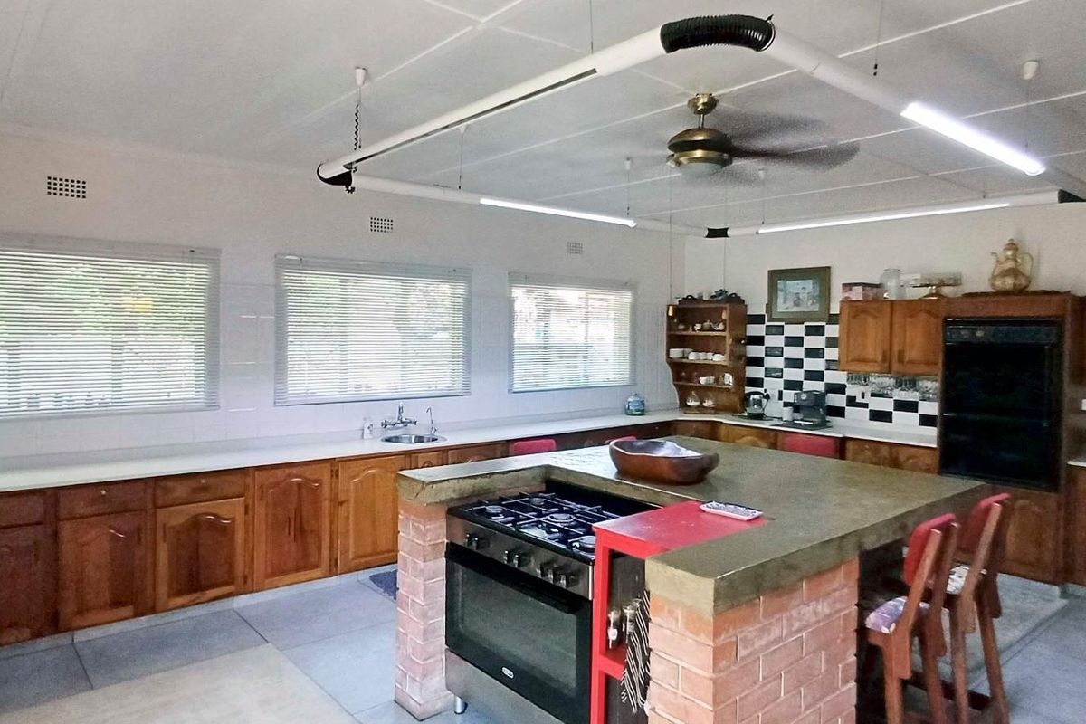 Spacious kitchen featuring extensive wooden cabinetry, a central brick-based island with a gas cooktop, and ample counter space with a tiled splashback.