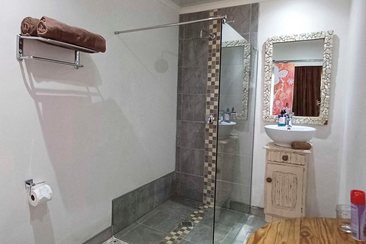 A functional bathroom featuring a walk-in shower with glass screen, a vessel sink vanity, and a standard toilet.