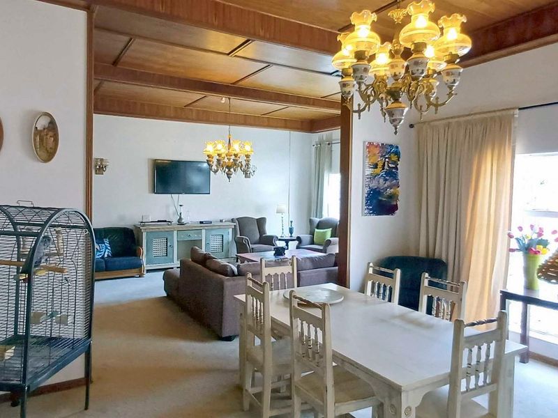 Spacious open-plan living and dining area featuring a distinctive exposed timber beam ceiling and large windows providing natural light.