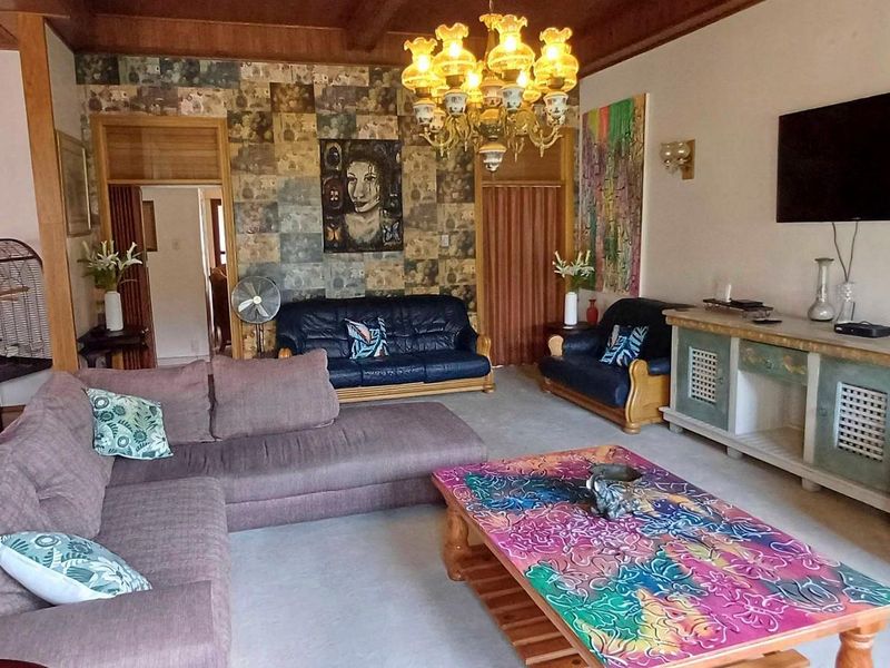 Spacious living room featuring exposed timber ceiling beams, decorative feature wallpaper, and a wall-mounted television setup.