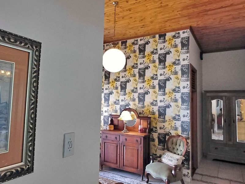 A hallway featuring a timber-clad ceiling, patterned wallpaper, and tiled flooring, providing a transition between living spaces.