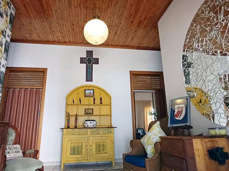 A living area featuring a warm timber tongue and groove ceiling, tiled flooring, and traditional wooden door frames.