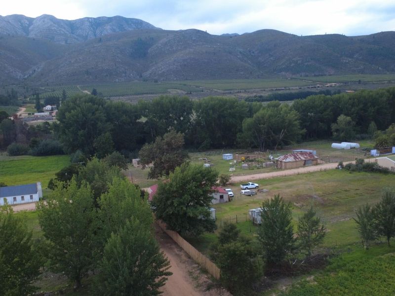 Aerial view of a rural property featuring multiple outbuildings, dirt access roads, and expansive mountain views in a natural landscape setting.