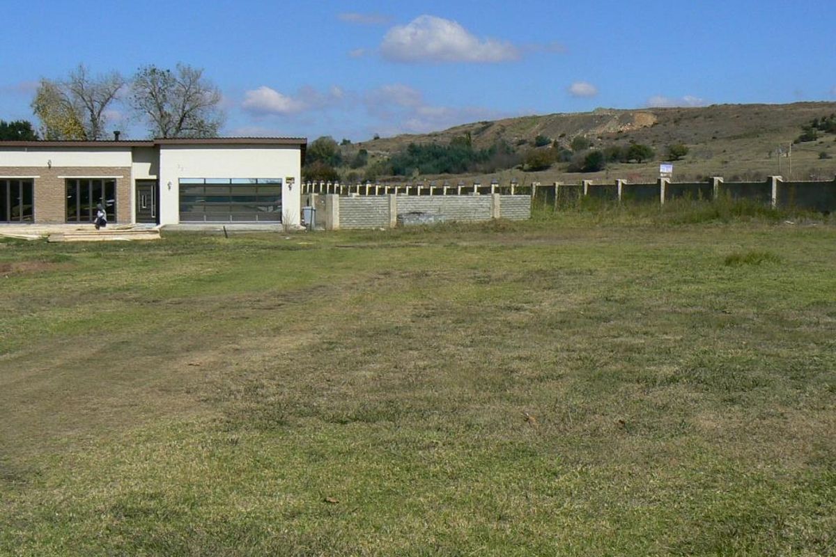 A view of the rear yard featuring a grass lawn, perimeter wall, and the rear elevation of the residential structure.