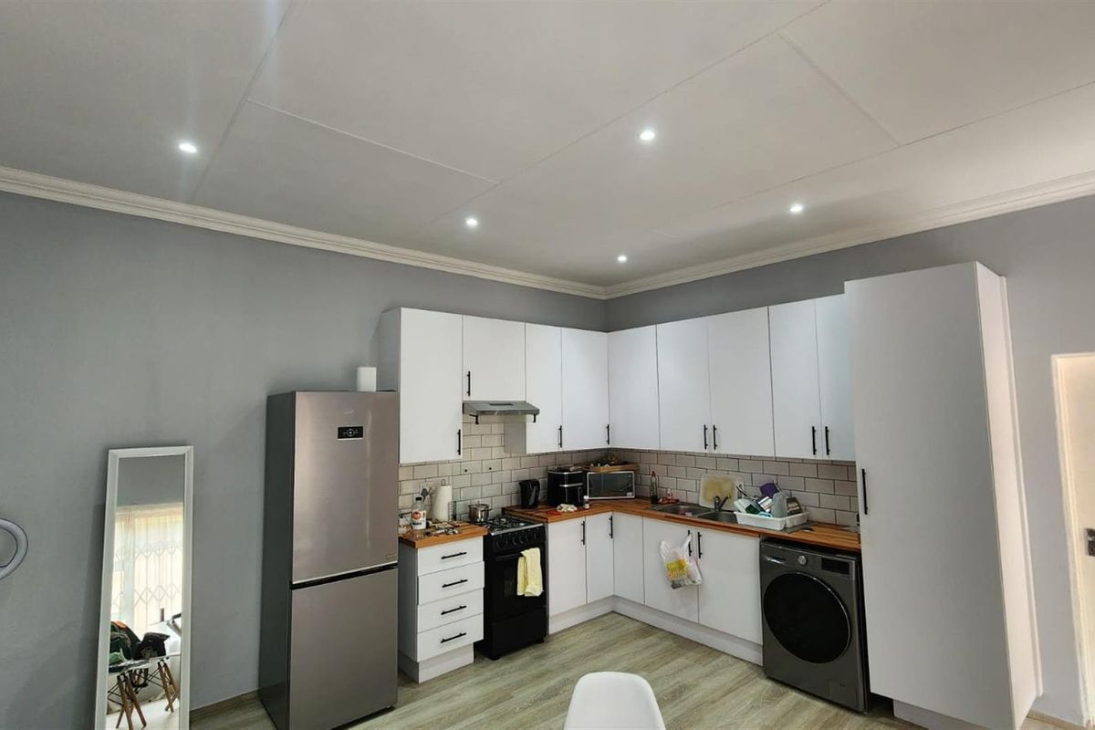 A functional kitchen featuring white cabinetry, wood-look countertops, a subway tile backsplash, and integrated space for a washing machine.