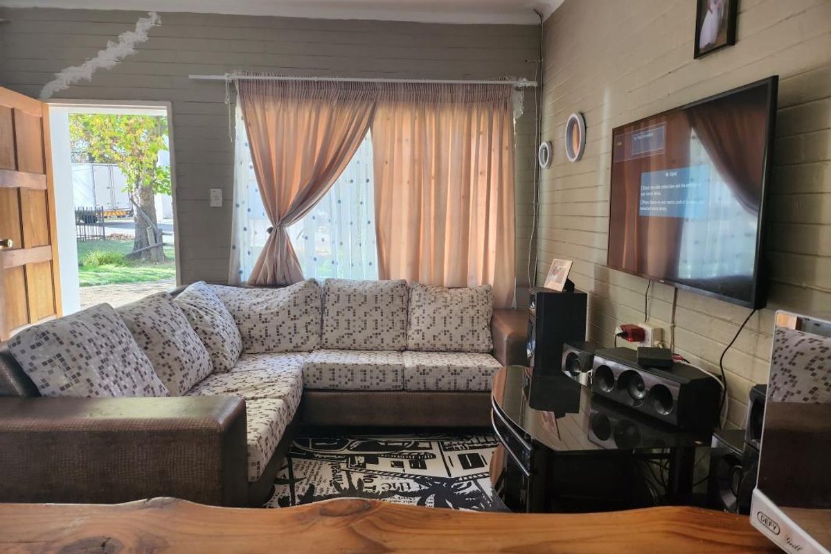 Living room featuring timber-clad walls and direct access to the exterior, offering a cozy layout with wall-mounted television space.