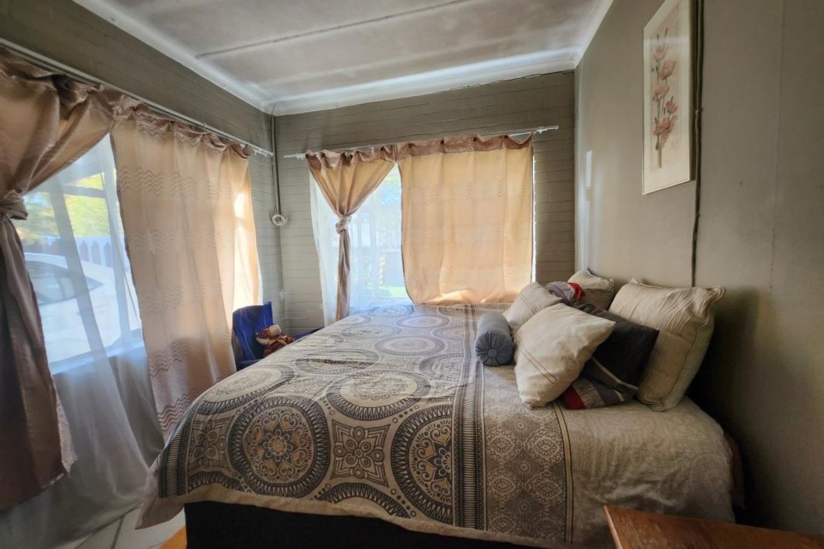 A bedroom featuring exposed brick walls, tiled flooring, and large windows allowing for natural light.