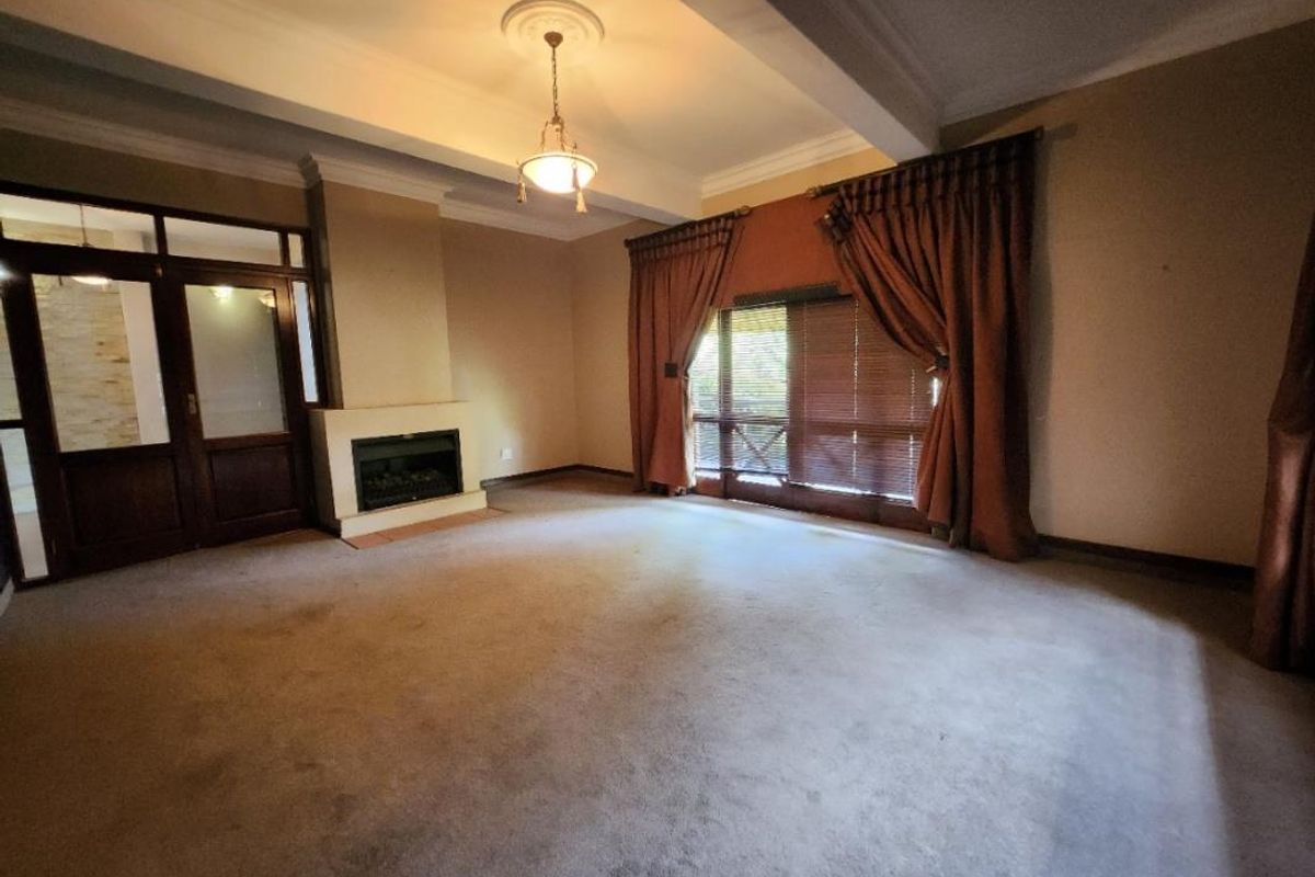 Spacious living room featuring a fireplace, decorative ceiling rose, and timber-framed glass doors leading to the exterior.