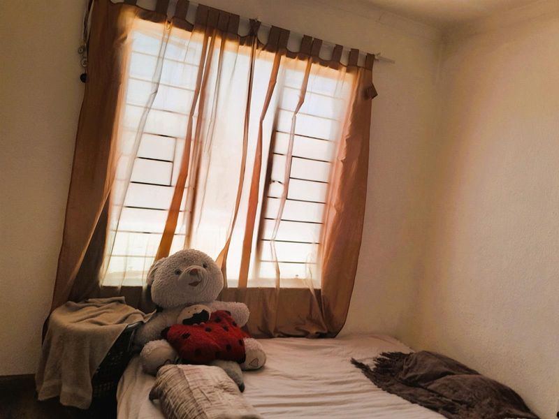 A bedroom featuring a window with installed security bars and curtain rod, providing natural light to the space.