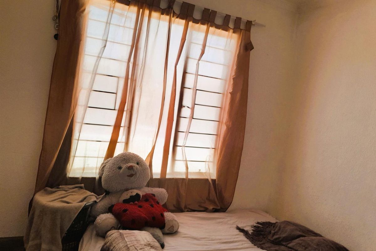 A bedroom featuring a window with installed security bars and curtain rod, providing natural light to the space.