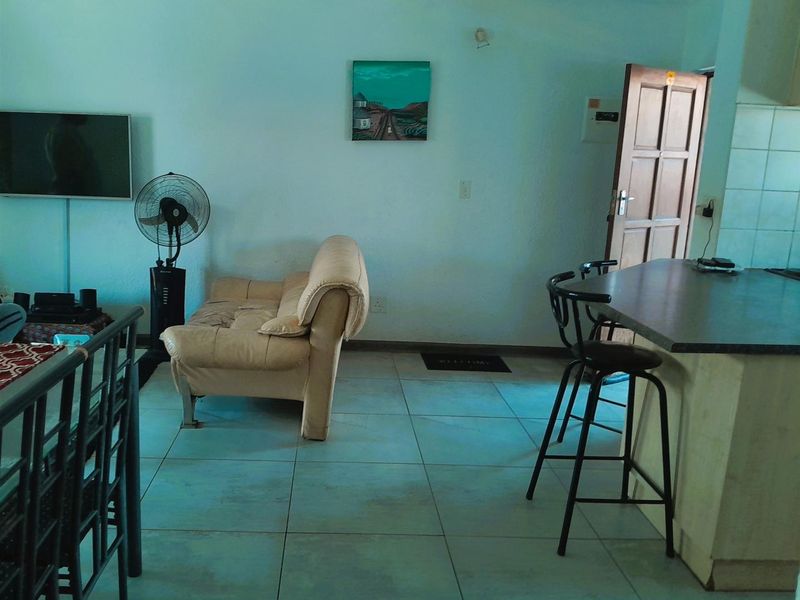 Open-plan living and kitchen area featuring tiled flooring and a breakfast bar, providing a functional layout for daily living.