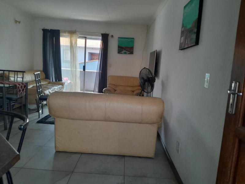 A living room area featuring tiled flooring and a sliding glass door providing access to an outdoor space.