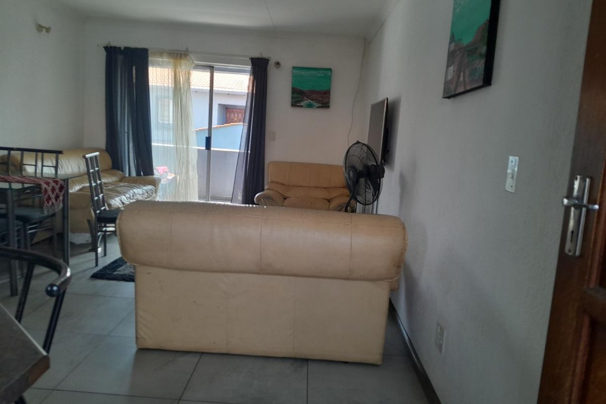 A living room area featuring tiled flooring and a sliding glass door providing access to an outdoor space.