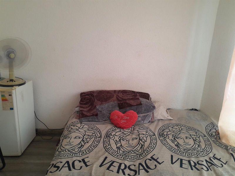 A simple bedroom featuring laminate flooring and neutral wall finishes, providing a functional space for rest.