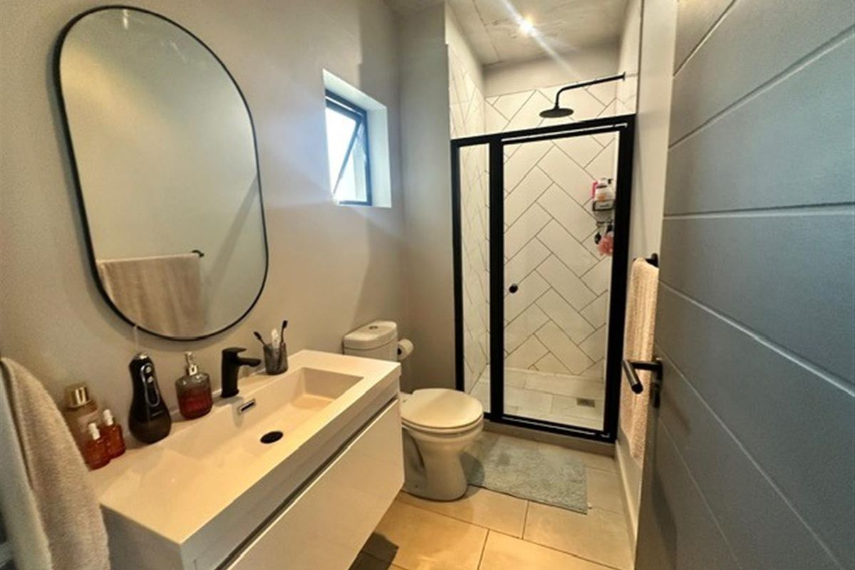 Modern bathroom featuring a floating vanity, walk-in shower with black frame, herringbone wall tiles, and contemporary fixtures.