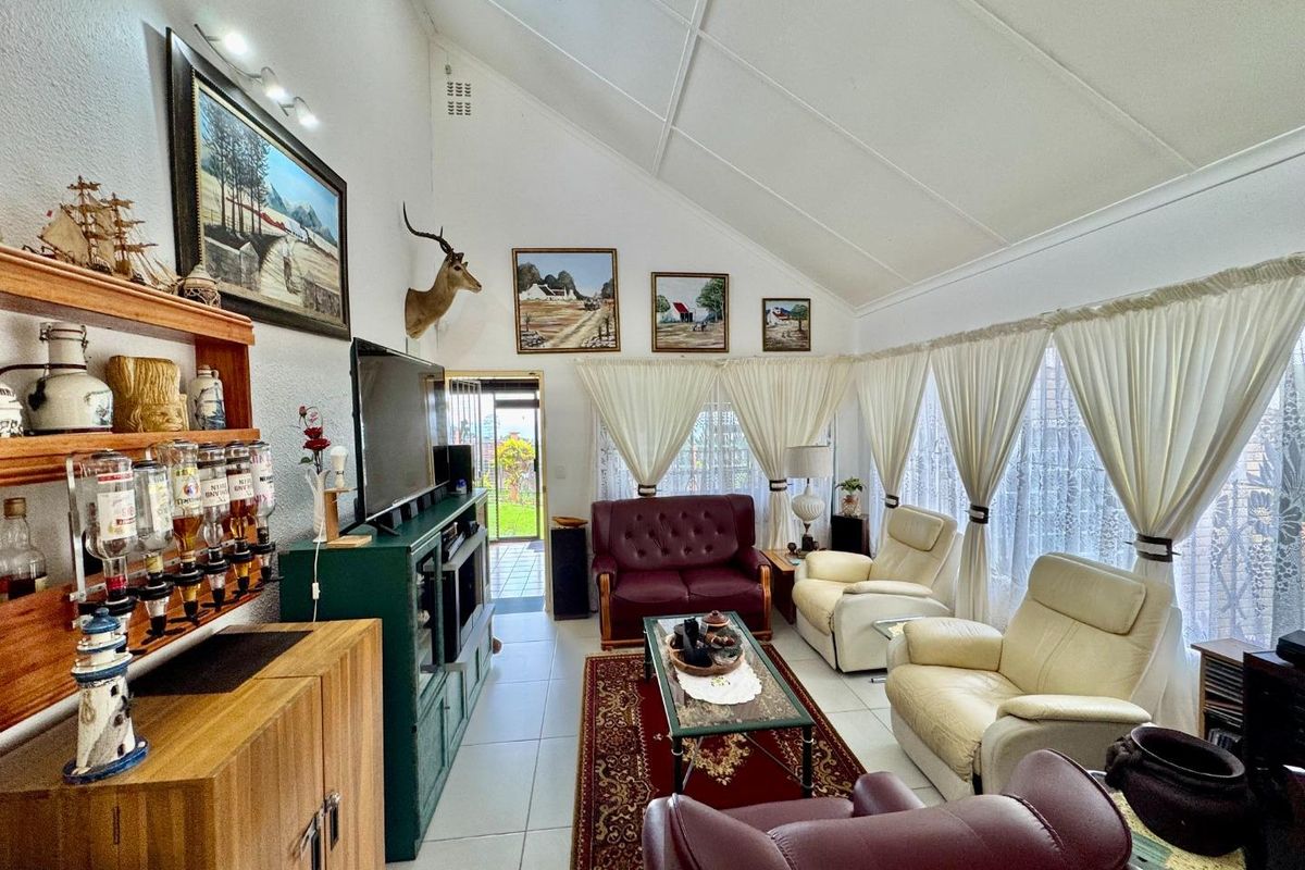 Spacious living room featuring high vaulted ceilings, tiled flooring, and large windows with natural light, providing a comfortable and airy atmosphere.