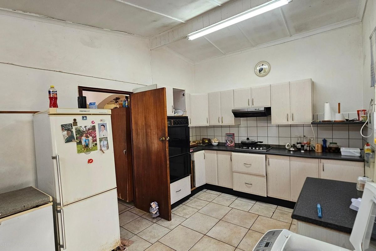 A functional kitchen featuring built-in cabinetry, a gas hob, extractor fan, and built-in oven, with tiled flooring and backsplash throughout.