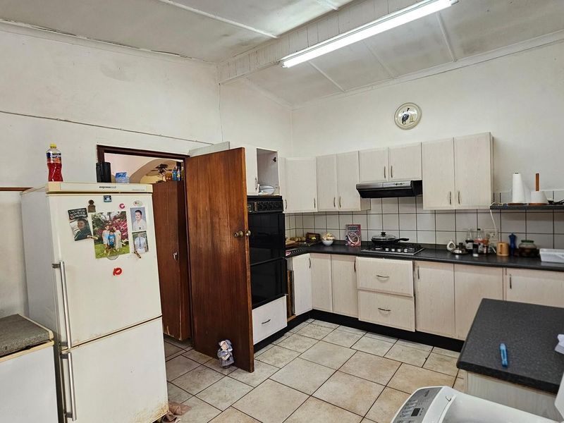 A functional kitchen featuring built-in cabinetry, a gas hob, extractor fan, and built-in oven, with tiled flooring and backsplash throughout.