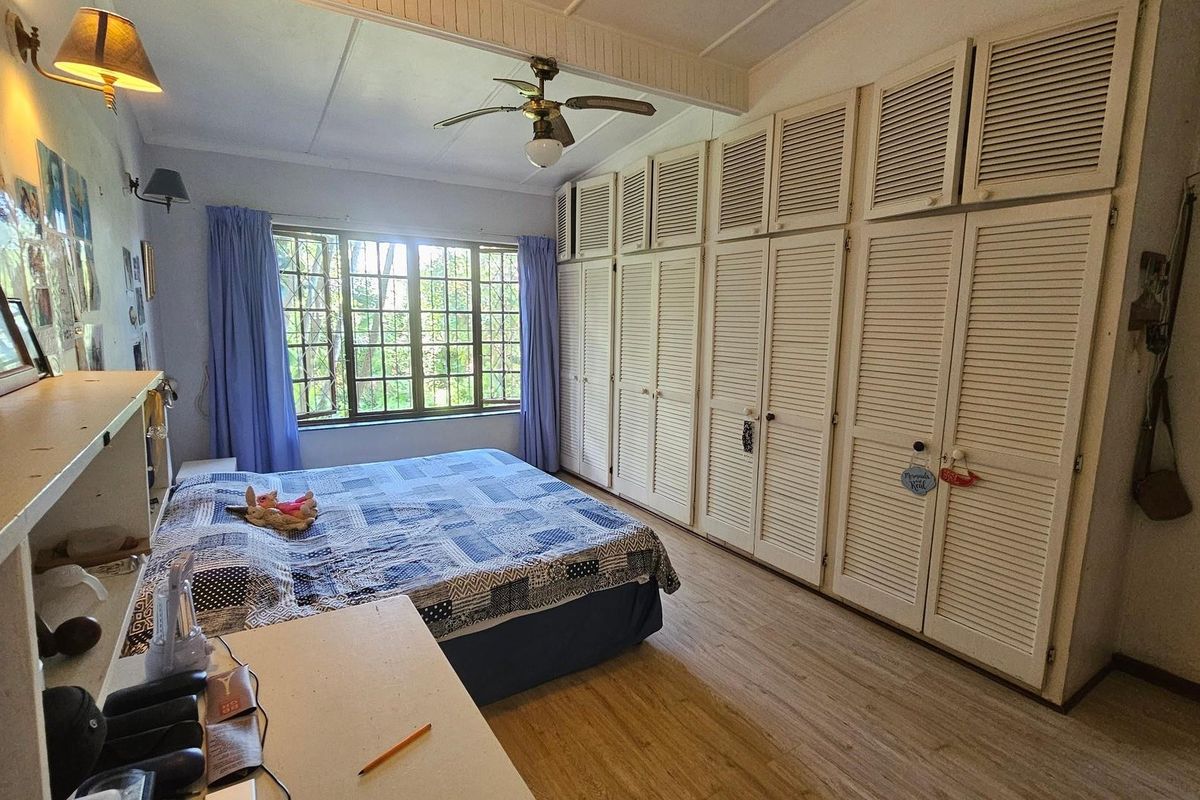A bedroom featuring extensive built-in louvered cupboards, a ceiling fan, and laminate flooring, offering ample storage space.