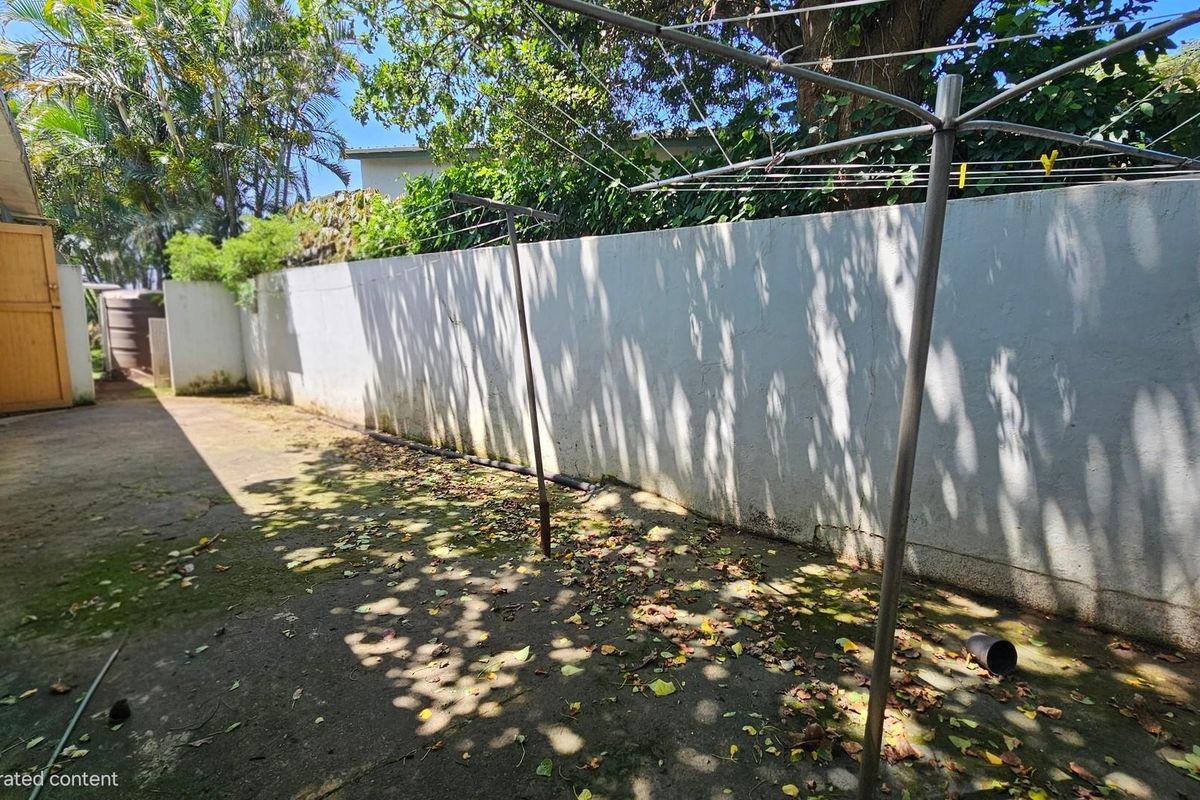 A rear exterior area featuring concrete paving, a boundary wall, and a rotary clothesline, requiring maintenance and landscaping to improve its overall appeal.
