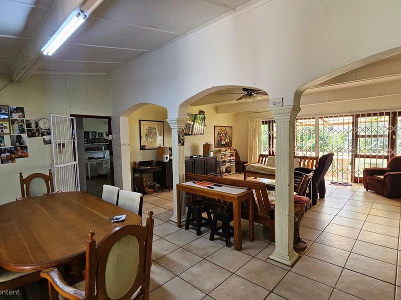 Open plan living and dining area featuring ceramic floor tiles, arched architectural details, and direct access to an outdoor patio through security gates.