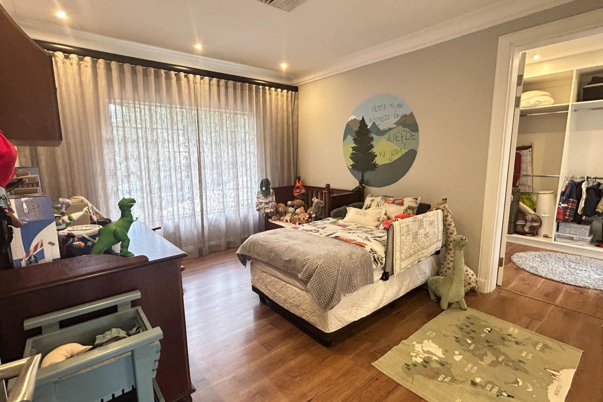 A well-maintained bedroom featuring wood-look flooring, recessed ceiling lighting, and an integrated walk-in closet with built-in shelving and hanging rails.